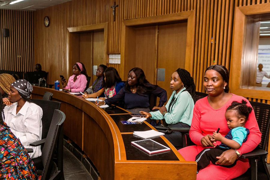 A cohort seated in the lecture hall, one parent with her baby